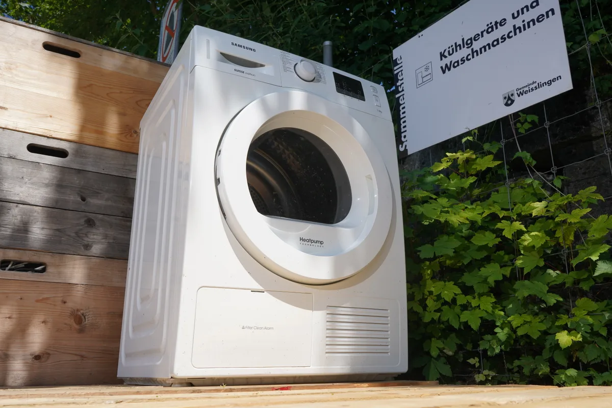 Man sieht eine alte Waschmaschine in der Wertstoffsammelstelle.